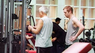 A super senior shows young guy how to lift some weights.A super senior shows young guy how to lift some weights.