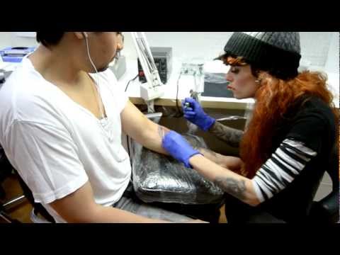 Leti tattoos a peacock feather on forearm at House of Tattoos Amsterdam