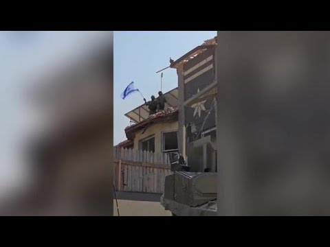 Soldati israeliani innalzano la bandiera su una casa di Gaza