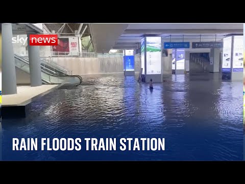 Floodwater pours down stairs at train station after heavy rain