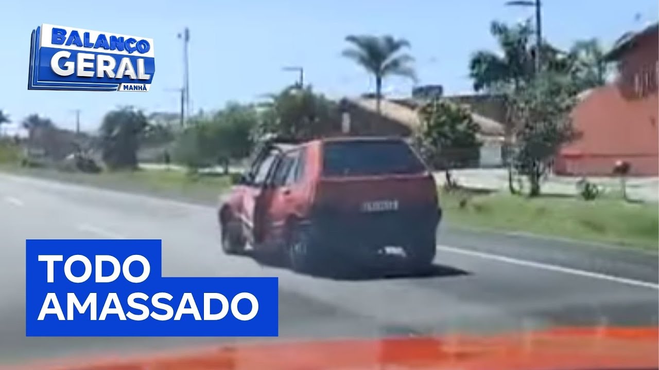 Carro amassado circula com porta aberta em rodovia de SP