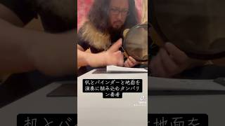 机とバインダーと地面を演奏に組み込むタンバリン奏者