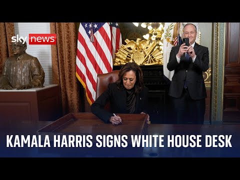 US Vice President Kamala Harris signs her desk in the ceremonial White House office
